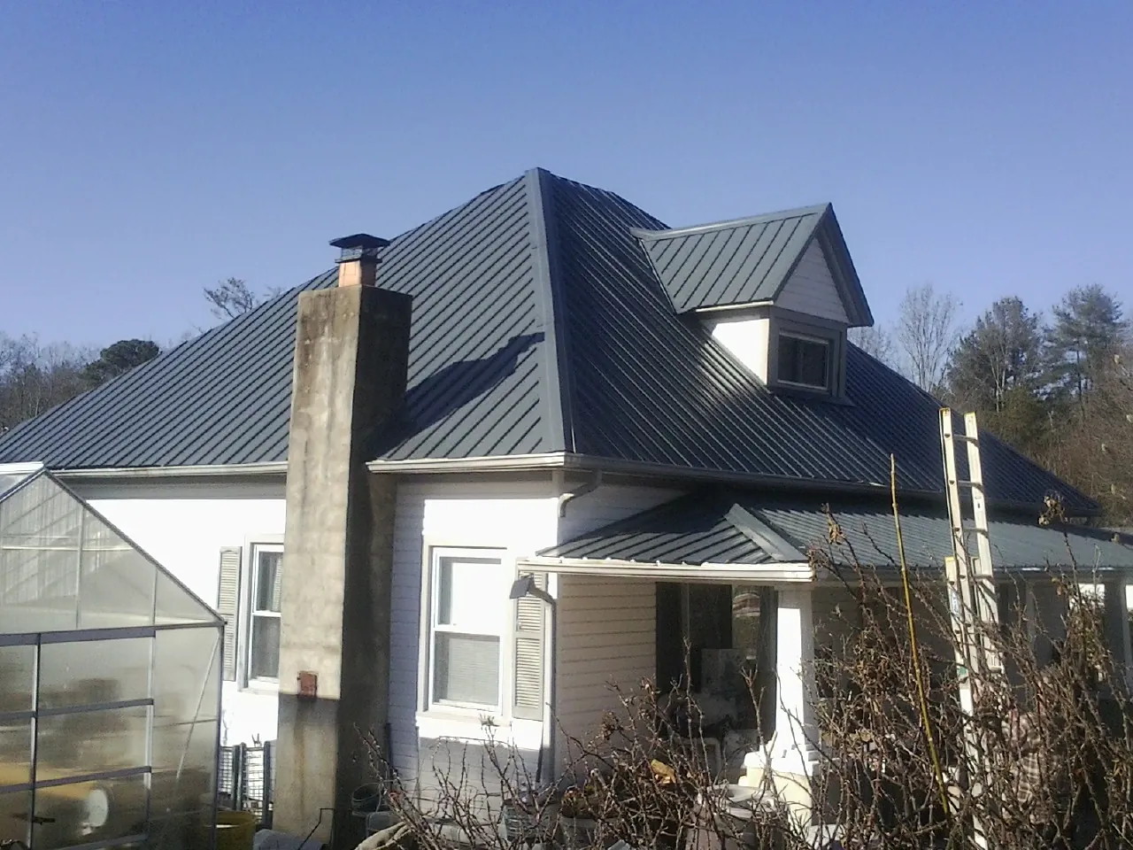 Dark blue standing seam metal roof on a white farmhouse with dormer — Slate & Tile Roof Repair by Roofing Brothers in University Park