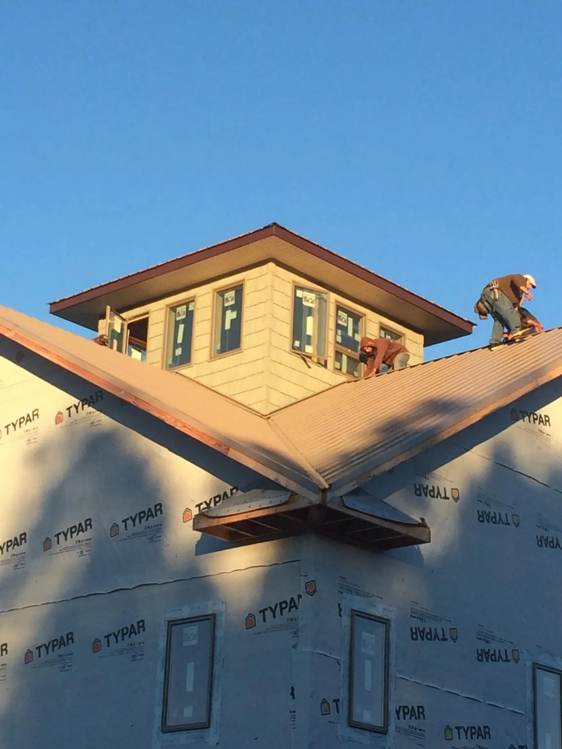 Roofers working around a rooftop cupola on a new metal roof at sunset — Roof Waterproofing in University Park by Roofing Brothers